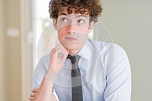 Young business man wearing a tie with hand on chin thinking about question, pensive expression