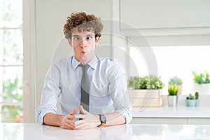 Young business man wearing a tie making fish face with lips, crazy and comical gesture