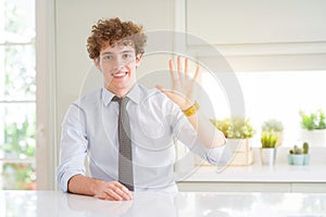 Young business man wearing a tie showing and pointing up with fingers number five while smiling confident and happy