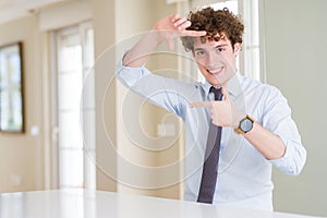 Young business man wearing a tie smiling making frame with hands and fingers with happy face