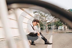 Young business man who lost job abandoned lost in depression sitting on ground street subway suffering emotional pain, thinking