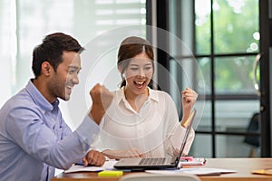 young business man and woman Startup coworkers working together looking at laptop and celebrating