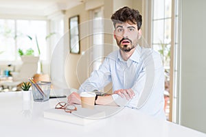 Young business man working afraid and shocked with surprise expression, fear and excited face