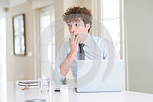Young business man working with computer laptop at the office bored yawning tired covering mouth with hand