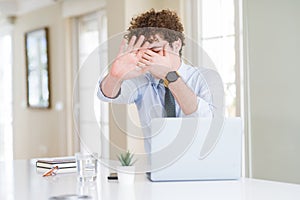 Young business man working with computer laptop at the office covering eyes with hands and doing stop gesture with sad and fear