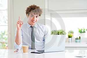 Young business man working with computer laptop at the office surprised with an idea or question pointing finger with happy face,