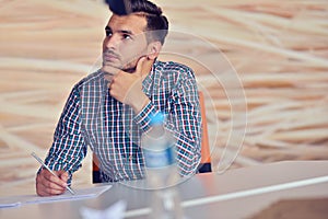 Young business man working on desktop computer at his desk in modern bright startup office interior