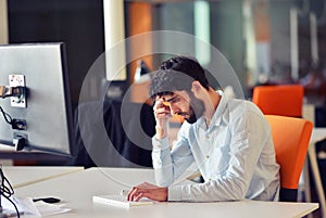 Young business man working on desktop computer at his desk in modern bright startup office interior