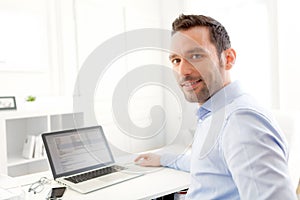 Mladý obchodník pracovní na na jeho přenosný počítač 