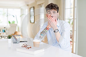 Young business man working shocked covering mouth with hands for mistake
