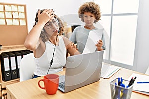 Young business mother working at the office with kid stressed and frustrated with hand on head, surprised and angry face