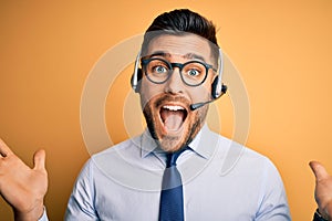 Young business operator man wearing customer service headset from call center celebrating crazy and amazed for success with arms