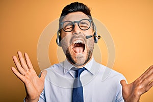 Young business operator man wearing customer service headset from call center celebrating mad and crazy for success with arms