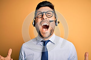 Young business operator man wearing customer service headset from call center crazy and mad shouting and yelling with aggressive