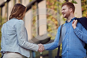 Young business partners shaking hands in front of a building