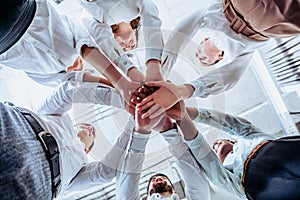 Young business people. The concept of unity and teamwork. Men and women joined in a circle with their hands together in a huddle
