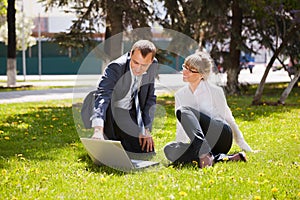 Young business people using laptop in city park