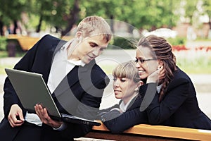 Young business people with laptop in city park