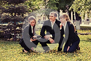 Young business people with laptop in city park