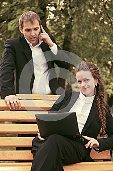 Young business people with laptop in city park