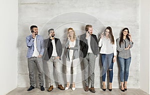 Young business people with mobile phone standing by the wall