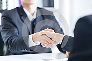 Young business people shaking hands in the office. Finishing successful meeting. The businessmen and businesswoman handshake after