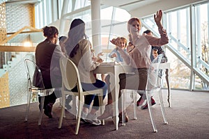 Young business people are sitting around the table during a lunch break in the company building and having a good time while