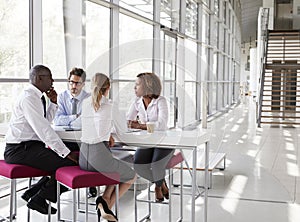 Young business people talking in modern lobby, full length