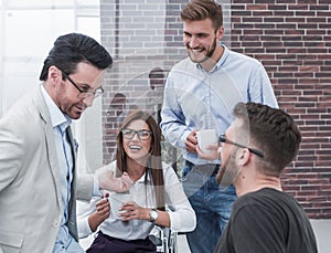 Young business people are talking and smiling during the coffee break in office