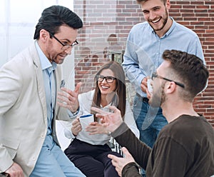 Young business people are talking and smiling during the coffee break in office