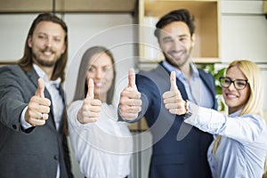 Young business people with thumb up standing in the office