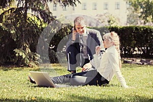 Young business people using laptop in city park