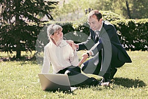 Young business people using laptop in city park