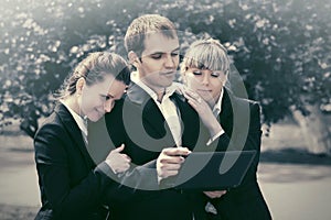 Young business people using laptop in city park