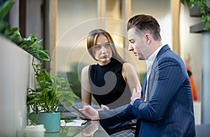 Young Business Persons Having Discussion While Holding Digital Tablet Sitting At Cafe.