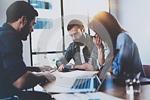 Young business professionals discussing new business project in modern office. Group of three coworkers brainstorming at