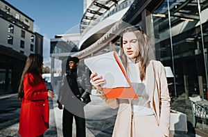 Young business professionals discussing work documents outdoors in urban setting.