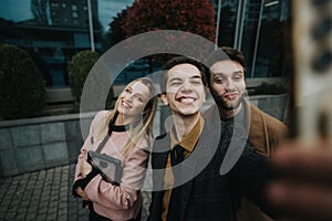 Young business professionals smiling while taking a group selfie outdoors