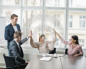 Young business team doing high five at conference table
