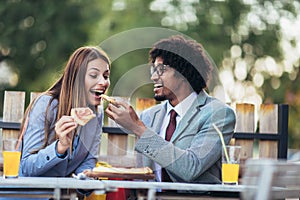 Young business team eating pizza in outdoor cafe.Business,food and people concept