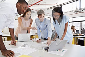 Young business team work standing at desk in a busy office