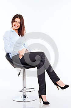 Young business woman in blue shirt sitting on the modern chair against white