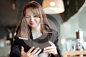 Young business woman in a cafe reading an ebook and drinking coffee