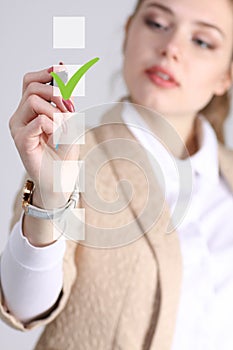 Young business woman checking on checklist box. Gray background.