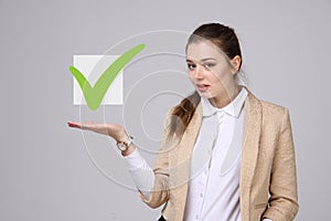 Young business woman checking on checklist box. Gray background.