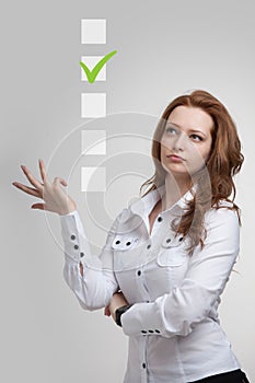 Young business woman checking on checklist box. Gray background.