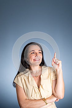 Young business woman, cheerful, pointing her left finger up