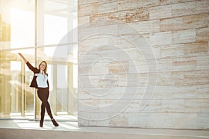 Young business woman cheering outside corporate building, success concept