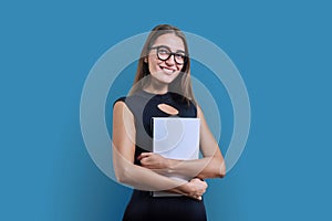 Young business woman with clipboard looking at camera on blue background