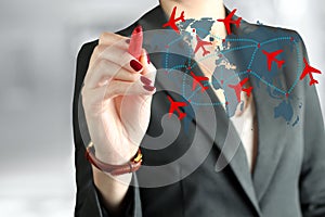 Young business woman drawing an airplane routes on world map.